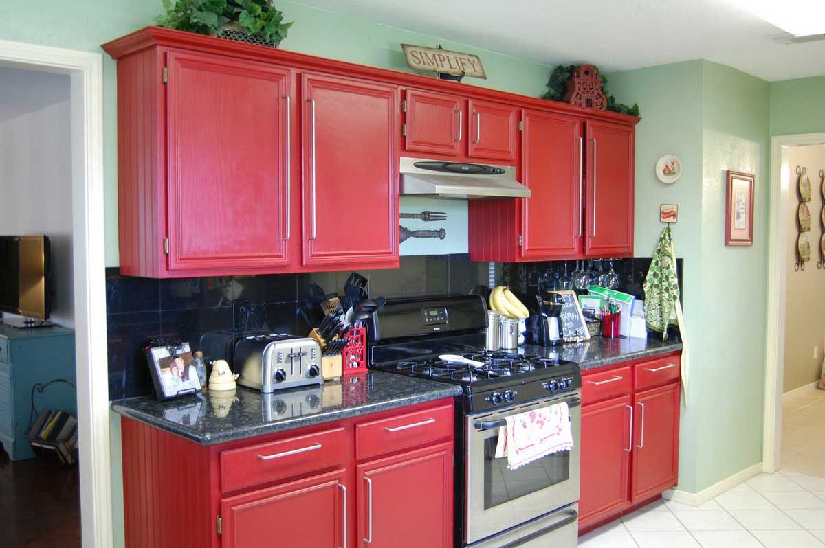 simple-petite-cuisinière à gaz-métal-entre-grandes-armoires-de-cuisine-rouges-close-green-wall-paint